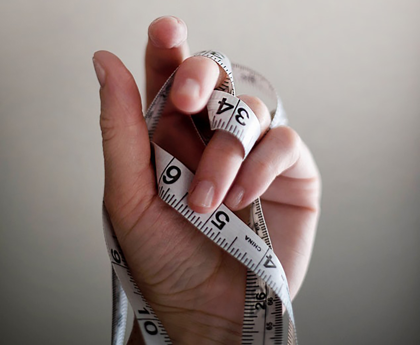 The hand of a new homeowner holding up a measuring tape