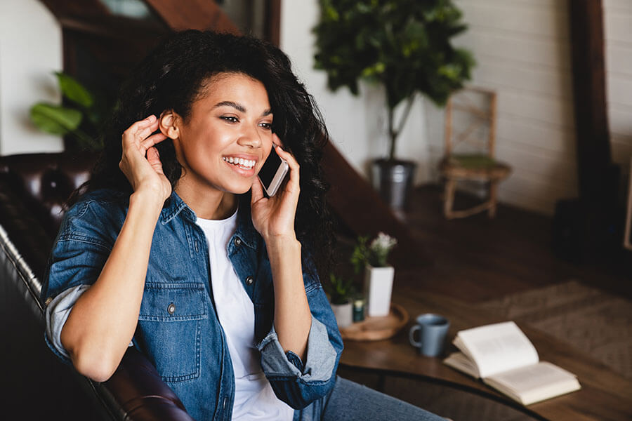 A lady smiles as she talks on the phone to her credit union.