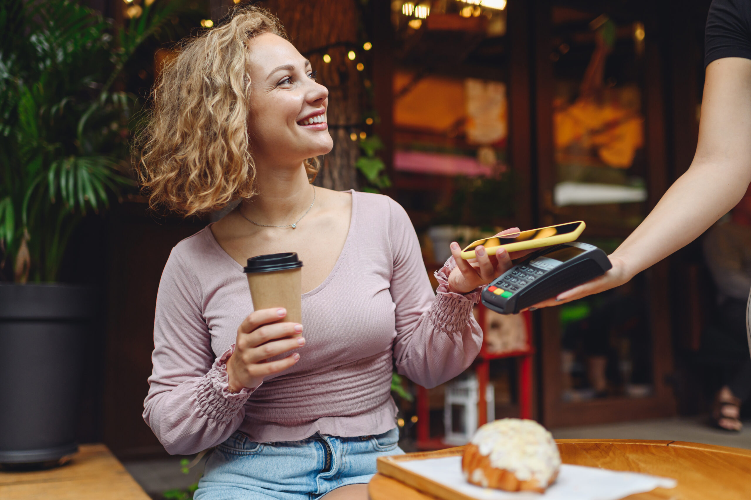 A woman makes a digital wallet payment at a coffee shop.