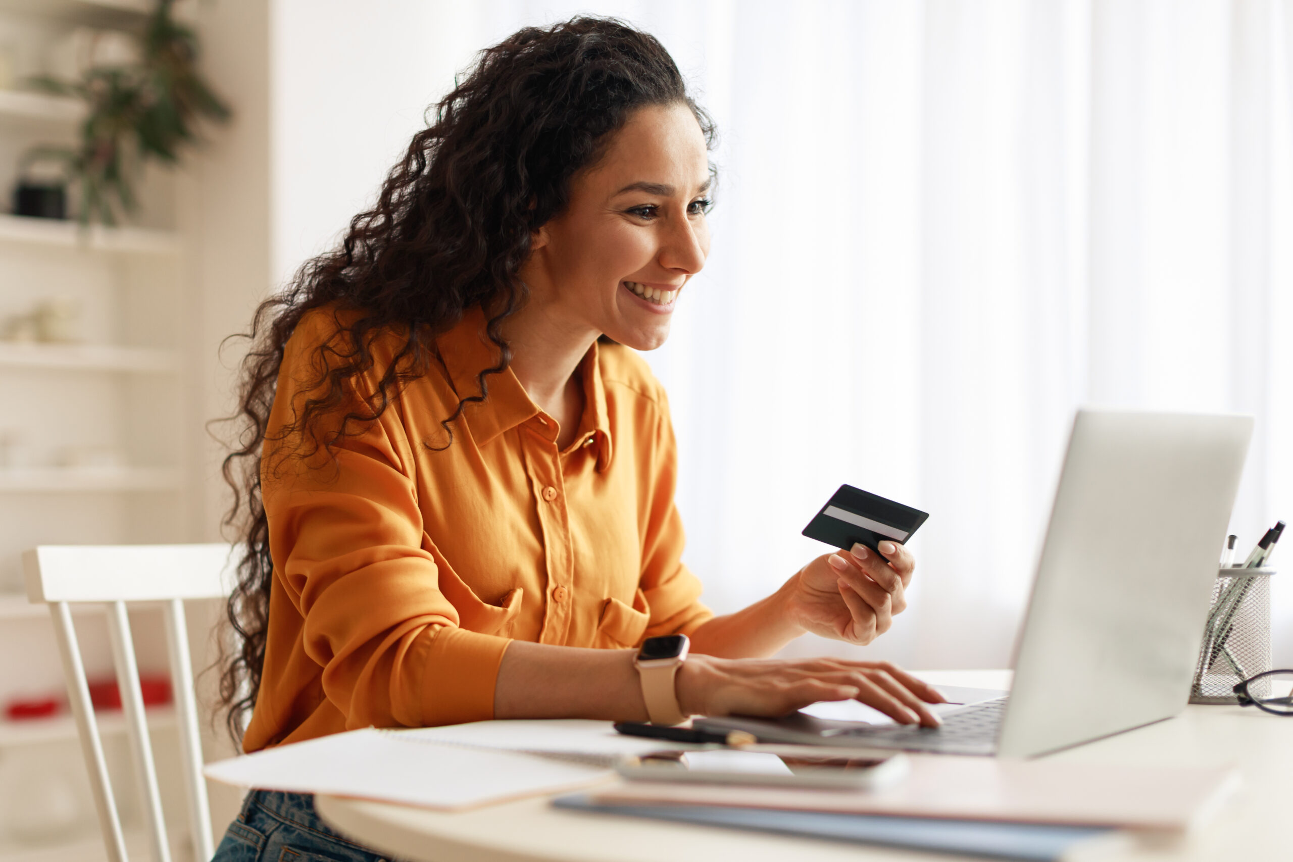 A woman grows her savings with the Spend and Save Program by making an online purchase with a credit union debit card.